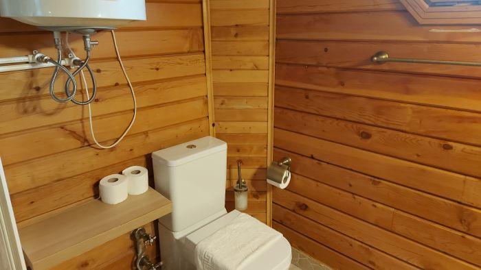 Experience the rustic charm of this wooden bathroom, offering comfort and convenience in a cozy setting.